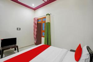 een slaapkamer met een rood en wit bed en een televisie bij OYO Flagship Hotel Midtown 2 in Noida