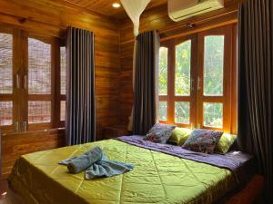 a bedroom with a bed in a room with windows at Nana Home, Entire Amazing Wooden Chalet in Phu Quoc