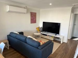 sala de estar con sofá azul y TV de pantalla plana en Central Evans Wagga Apartments, en Wagga Wagga