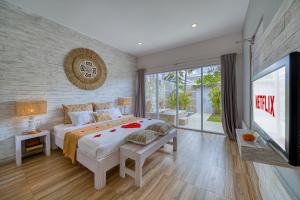 a bedroom with a large bed and a tv at Bali Cosy Villa Adults Only in Legian