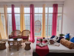 um quarto com uma cama com cortinas e cadeiras cor-de-rosa em 4REST INN PRIVATE LIMITED em Kodaikanal