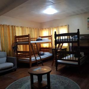a room with three bunk beds and a couch at Old Orangewood Bed & Breakfast in Baguio