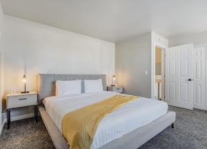 um quarto branco com uma cama grande e duas mesas de cabeceira em Pueblo Place Riverwalk Fireplace Pet-Friendly em Pueblo
