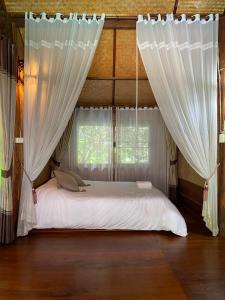 een slaapkamer met een bed met witte gordijnen bij Shaya’s Green Hideaway 