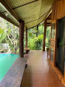 een veranda met een houten bank en een zwembad bij Shaya’s Green Hideaway 