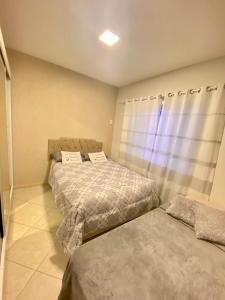 ein Schlafzimmer mit zwei Betten und einem Fenster in der Unterkunft Casa em Balneário Camboriú in Balneário Camboriú