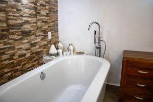 y baño con bañera blanca y pared de ladrillo. en Hotel Boutique Casa Tellez, 