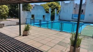 a swimming pool with a fence and two potted plants at Castillo Del Lago - Carlos Paz - D26 in Villa Carlos Paz