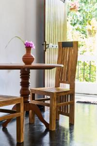 a wooden table and a chair and a vase with flowers on it at Daasa Guest Mirissa in Mirissa
