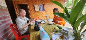 two men sitting at a table eating food at Pondok Wisata Noah in Likupang