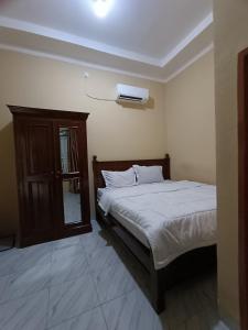um quarto com uma cama e uma televisão na parede em OYO 93340 Angsana Aglow Homestay em Duri