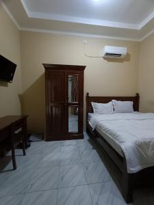 OYO 93340 Angsana Aglow Homestay في Duri: غرفة نوم بسرير وتلفزيون ومكتب