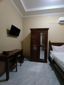 a bedroom with a bed and a desk and a television at OYO 93340 Angsana Aglow Homestay in Duri