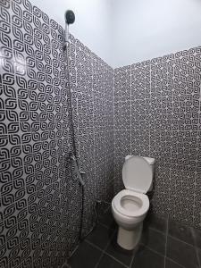 a bathroom with a toilet in a black and white wall at OYO 93340 Angsana Aglow Homestay in Duri