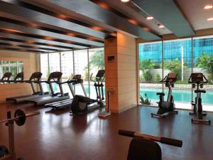 a gym with many treadmills and a swimming pool at 2br- Central Park Residence Alaina Tower Floor 29 in Jakarta