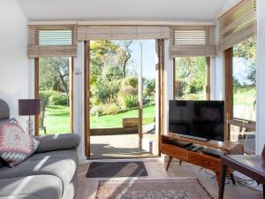 a living room with a couch and a tv and a window at Flaxpool Well Garden Room in Crowcombe