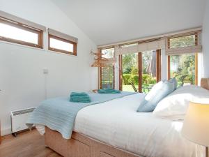a bedroom with a large white bed with windows at Flaxpool Well Garden Room in Crowcombe