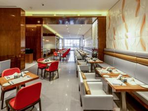 a dining room with tables and red chairs at Flora Al Barsha Hotel At The Mall in Dubai