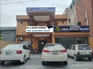 Hotel new royal palace في لاهور: ثلاث سيارات بيضاء تقف امام الفندق