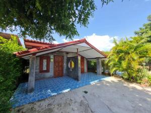 une petite maison avec une porte rouge et un palmier dans l'établissement บ้านสวน สระแก้ว รีสอร์ท, 