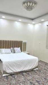 a bedroom with a large white bed and a chandelier at Traveler Rooms 2 in Al Madinah