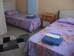 a bedroom with two beds with purple sheets and a table at Ernur Pension in Çanakkale