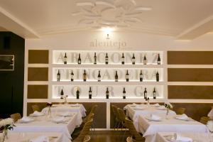 a restaurant with white tables and bottles of wine at Sever Rio Hotel in Marvão