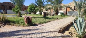a brick walkway in front of a building with palm trees at Sand Rose in Bawiti