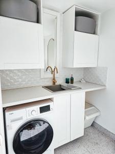 a white kitchen with a washing machine and a sink at 2 Min Walk to Beach Firepit Yard Kids welcome in Ettalong Beach