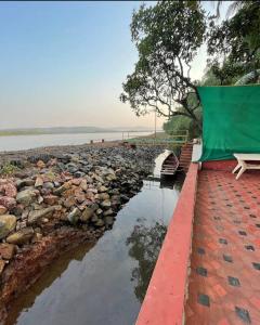 a bench sitting next to a body of water at Korjai kinara Homestay in Malvan