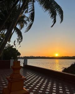 a sunset over a body of water with a palm tree at Korjai kinara Homestay in Malvan
