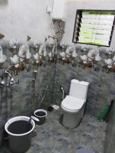 a bathroom with a toilet and flowers on the wall at Korjai kinara Homestay in Malvan