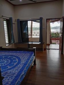 1 dormitorio con 1 cama y 2 ventanas grandes en Korjai kinara Homestay en Mālvan