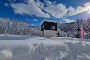 a small black and white building in the snow at Furano Hidden Hill【FHH】 in Kami-furano