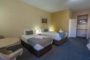 a hotel room with two beds and a table at Hospitality Kalgoorlie, SureStay Collection by Best Western in Kalgoorlie