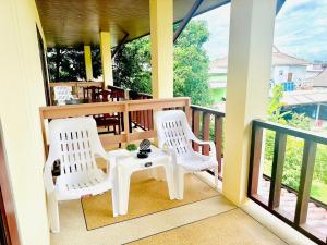 a porch with two white chairs and a table at Phumin Apartment in Ko Lanta