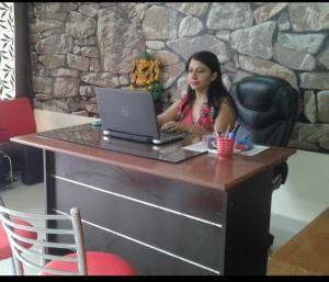 uma mulher sentada numa mesa com um laptop em New Chandigarh Holiday Home em Chandīgarh