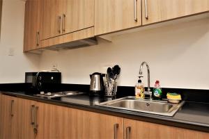 a kitchen with a stainless steel sink and wooden cabinets at MOA Pasay 1156 Shore Residences Hotel Vibe Staycation in Manila