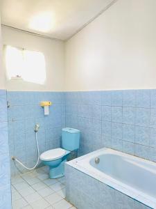 a bathroom with a blue toilet and a bath tub at suris bungalow 2 in Pabean Buleleng