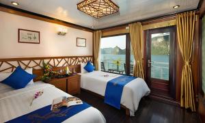 two beds in a room with a view of the water at Royal Palace Cruise in Ha Long