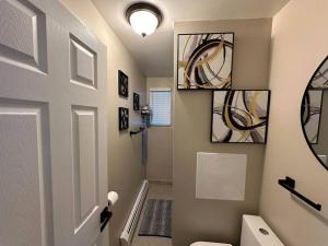 a bathroom with a toilet and paintings on the wall at Maiden Nest Private Master Suite in Pawtucket