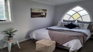een slaapkamer met een groot bed en een gewelfd raam bij Nonna's Retreat in Sussex inlet