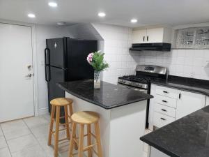 eine Küche mit einem schwarzen Kühlschrank und 2 Barhockern in der Unterkunft Tidy Private Rooms with Full Kitchen in Toronto