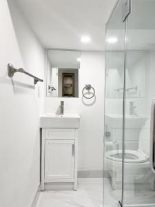 a white bathroom with a sink and a toilet at Tidy Private Rooms with Full Kitchen in Toronto