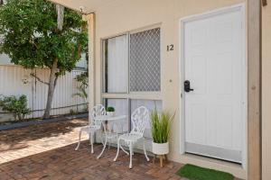 een patio met een tafel en stoelen en een deur bij Central Motel Mooloolaba in Mooloolaba +4 foto's