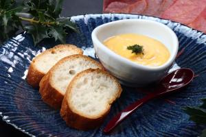 a blue plate with a bowl of soup and some bread at Baigetsu Ryokan in Shimo-suwa