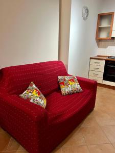 a red couch with two pillows on it in a kitchen at Sicilia Bedda Apartment in Messina