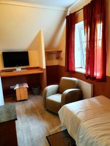 a hotel room with a bed and a chair and a television at Alt Enginger Mühle in Paderborn