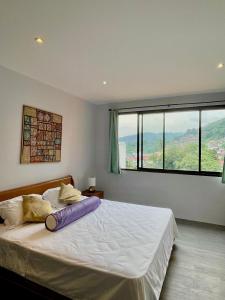 a bedroom with a large bed with a large window at 泰暖WarmThai（karon） in Karon Beach