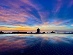 een uitzicht op de zonsondergang vanaf een zwembad met uitzicht op de lucht bij 泰暖WarmThai（karon） in Karon Beach